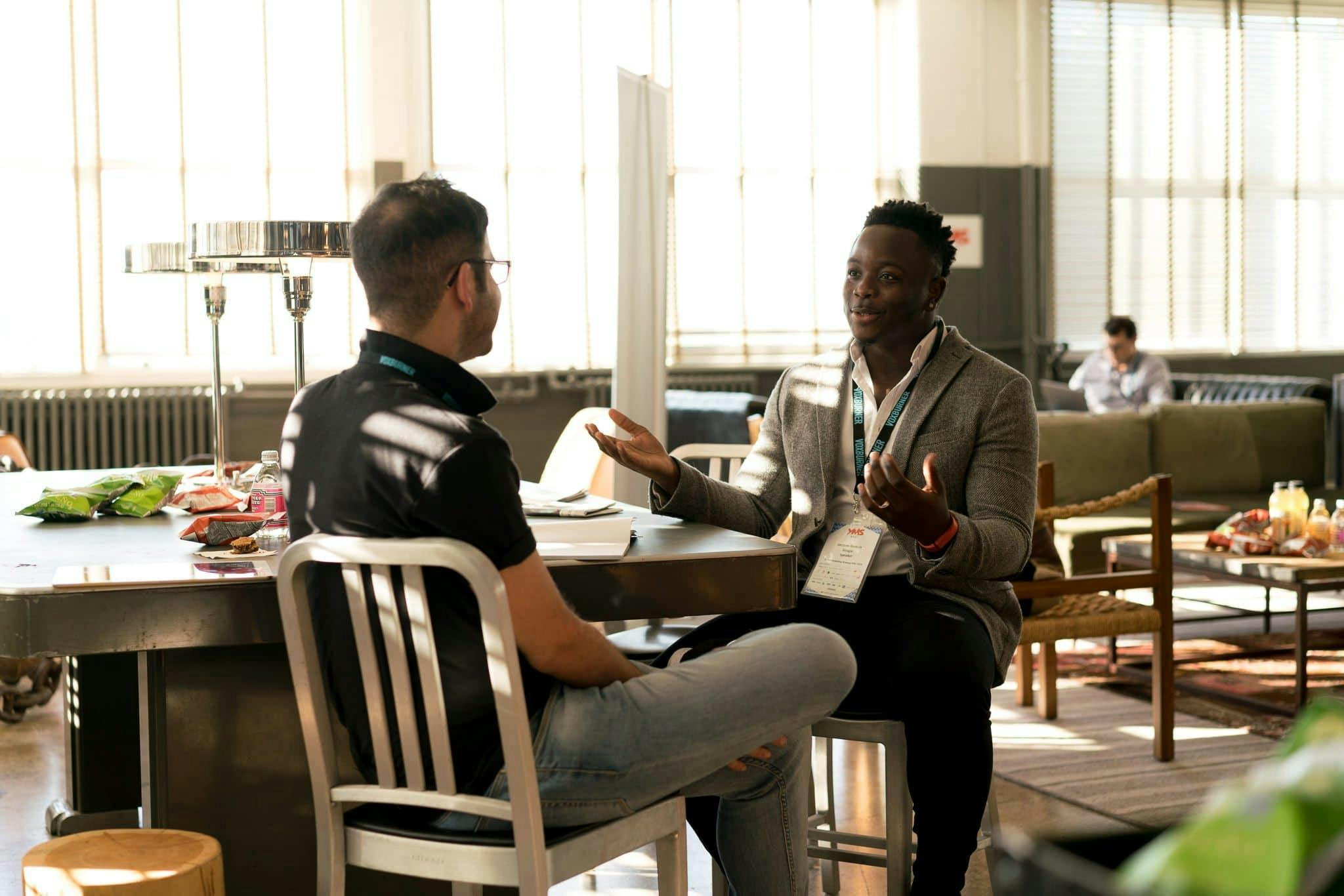 Home Two men having a casual discussion in a bright indoor setting, highlighting mentorship.